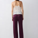 Woman wearing a white lace top and burgundy pants on a white background