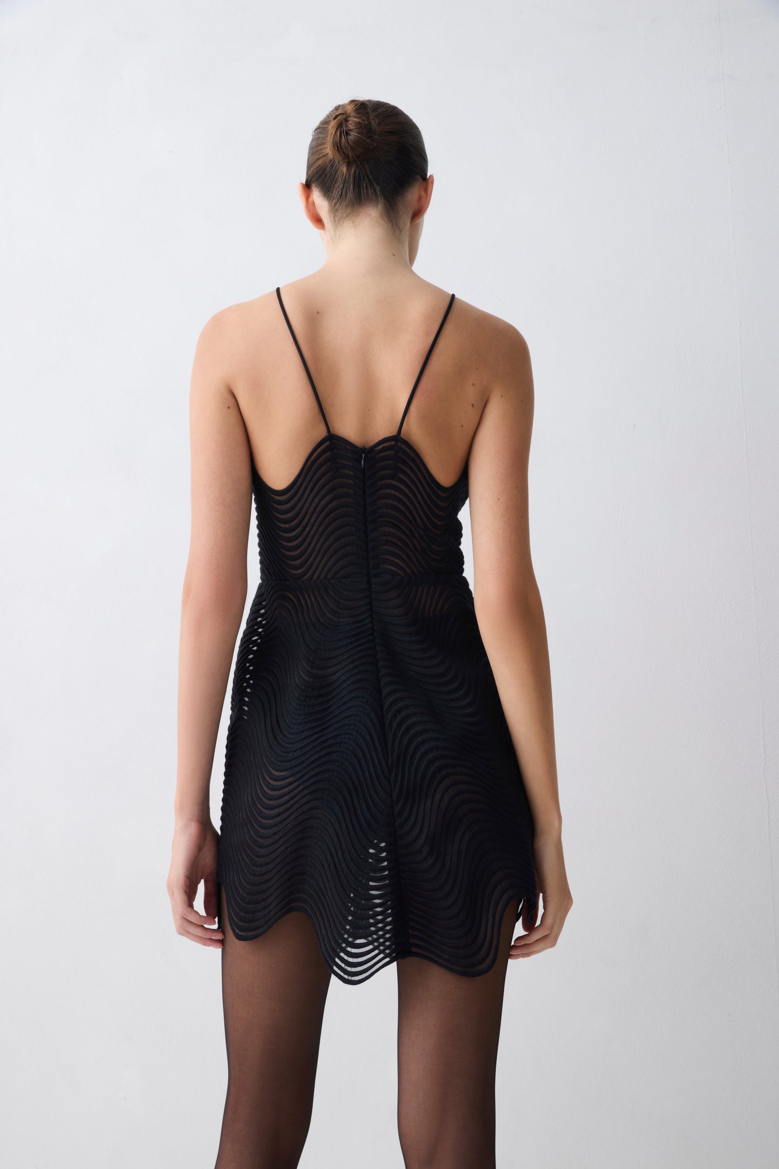 Black sleeveless dress with wavy pattern on a plain background
