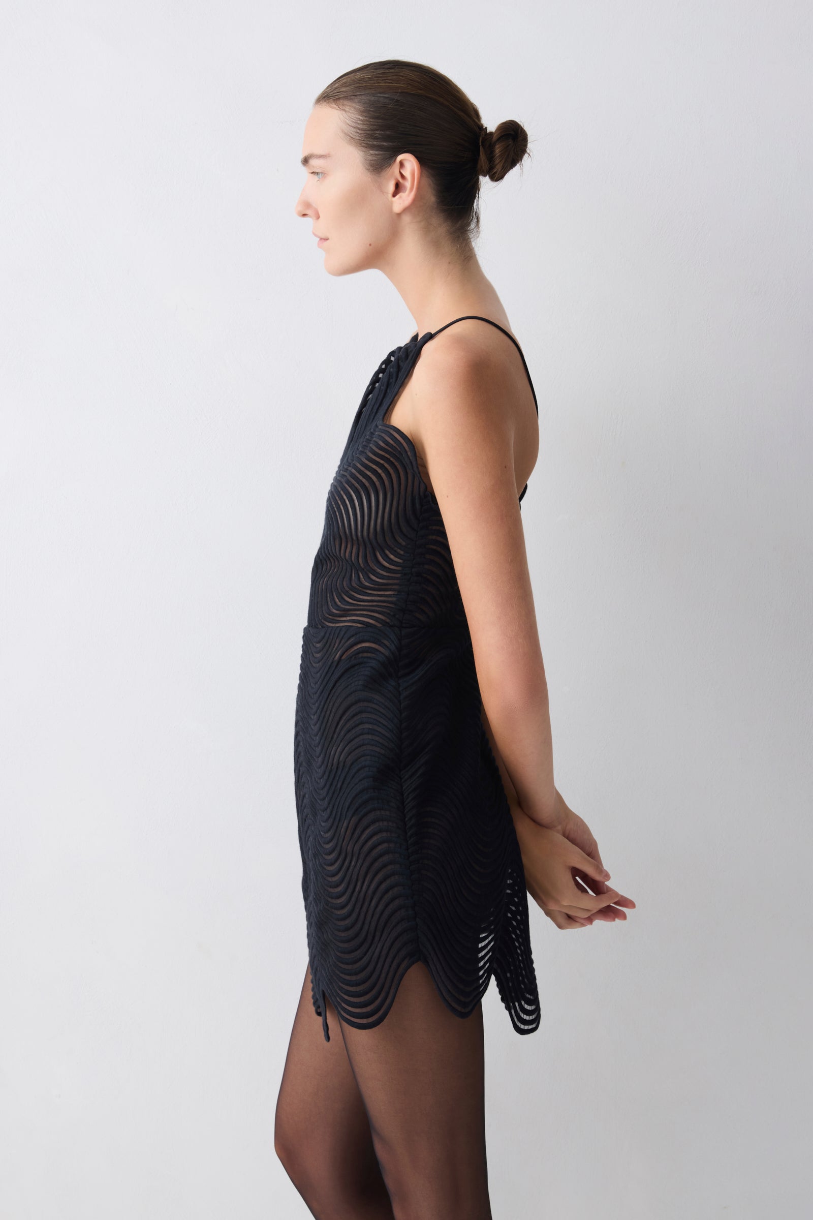 Black sleeveless dress with wavy pattern on a plain background