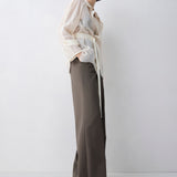 Woman wearing a patterned sweater and wide-leg pants on a white background