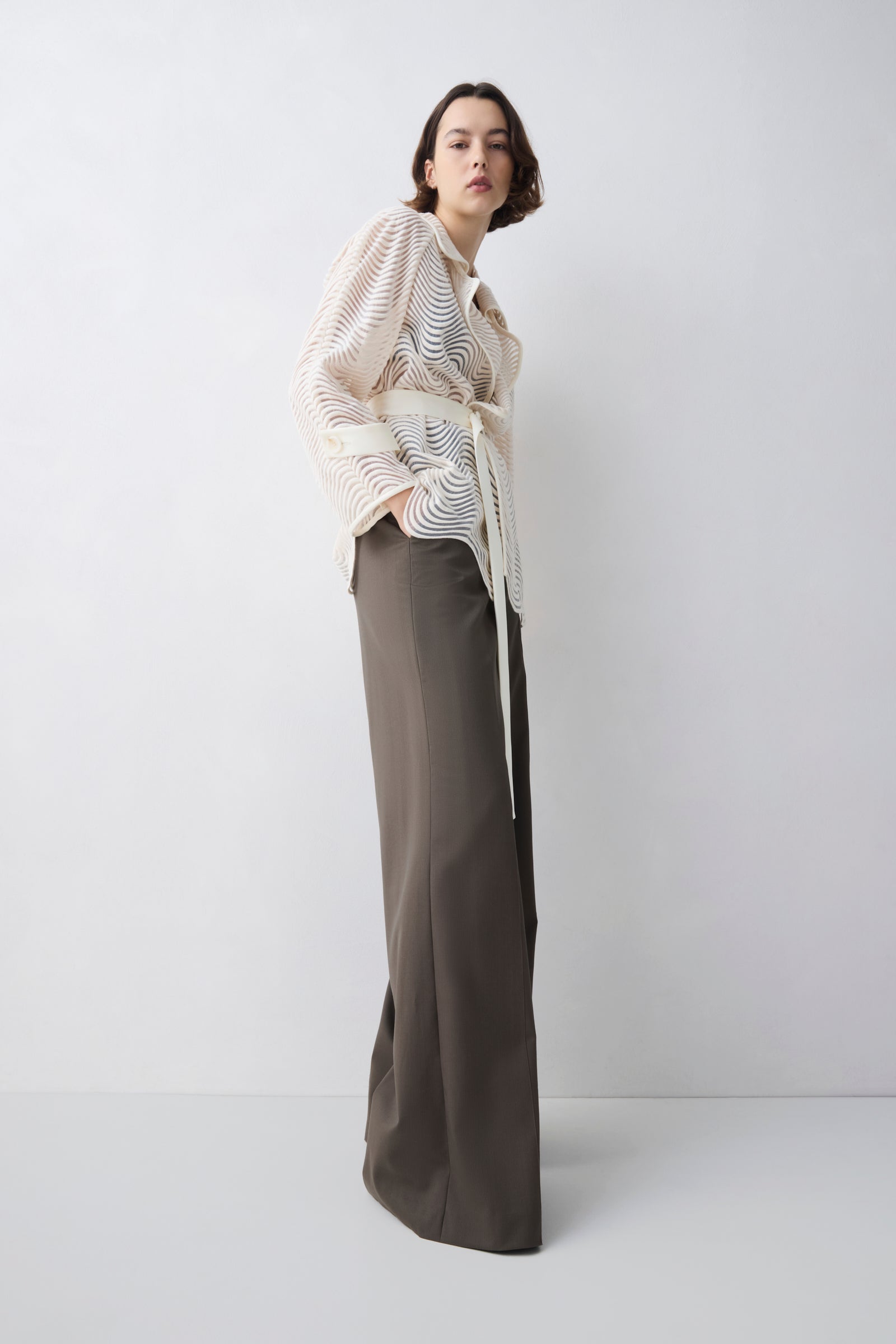Woman wearing a patterned sweater and wide-leg pants on a white background