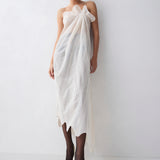 Woman wearing a white dress with a textured pattern against a plain background