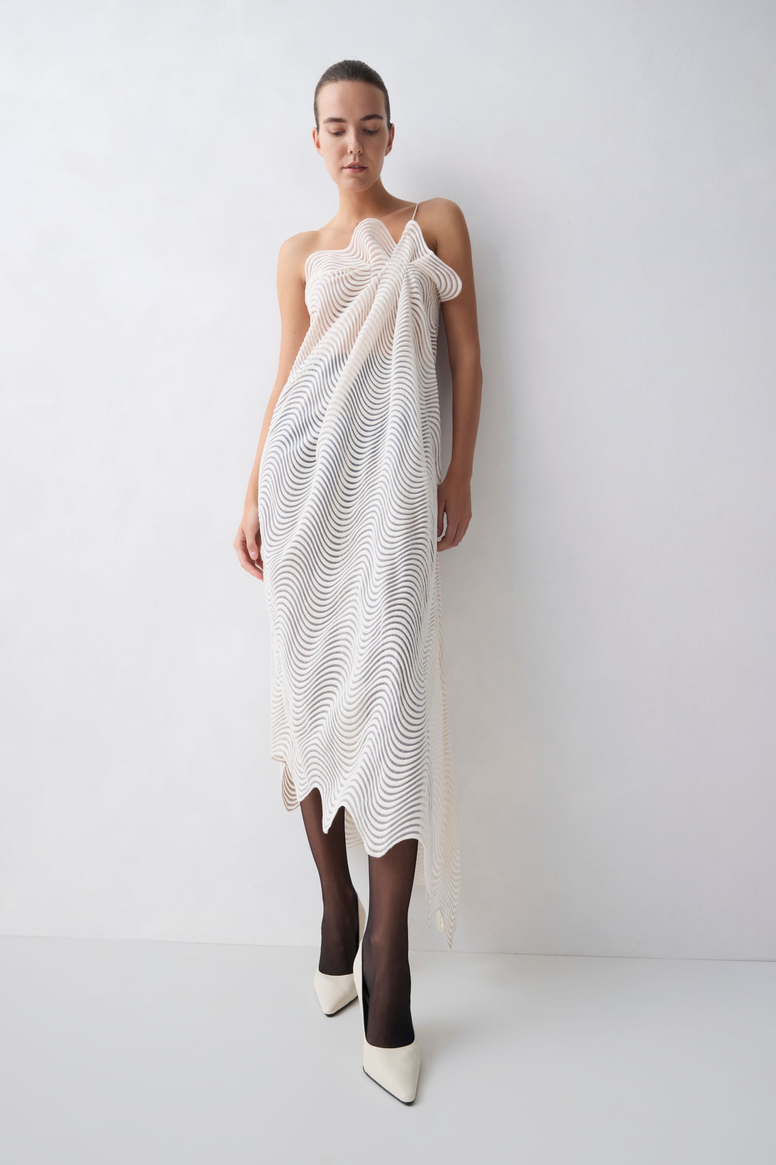 Woman wearing a white dress with a textured pattern against a plain background