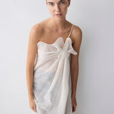 Woman wearing a white dress with black patterns against a plain background