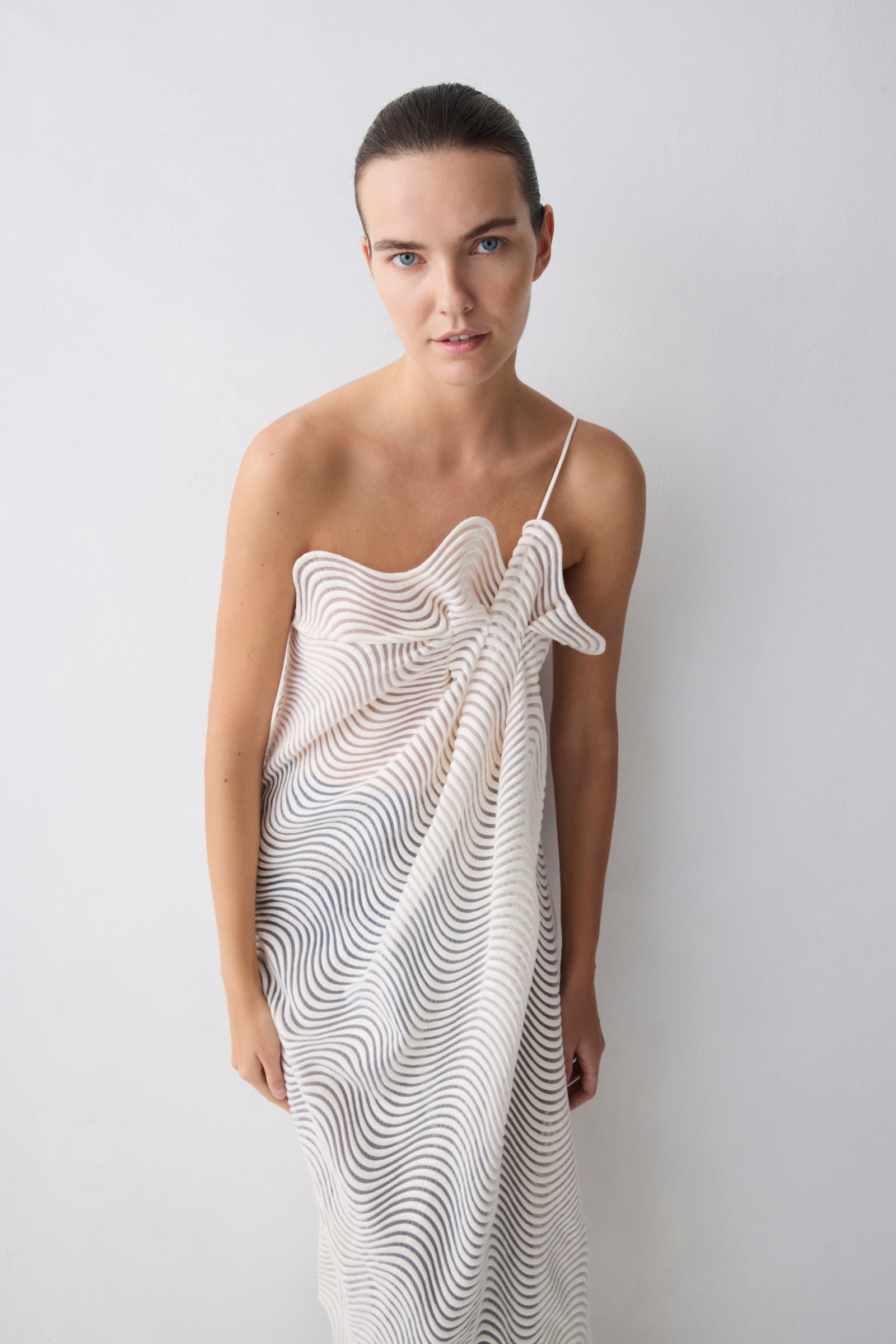 Woman wearing a white dress with black patterns against a plain background