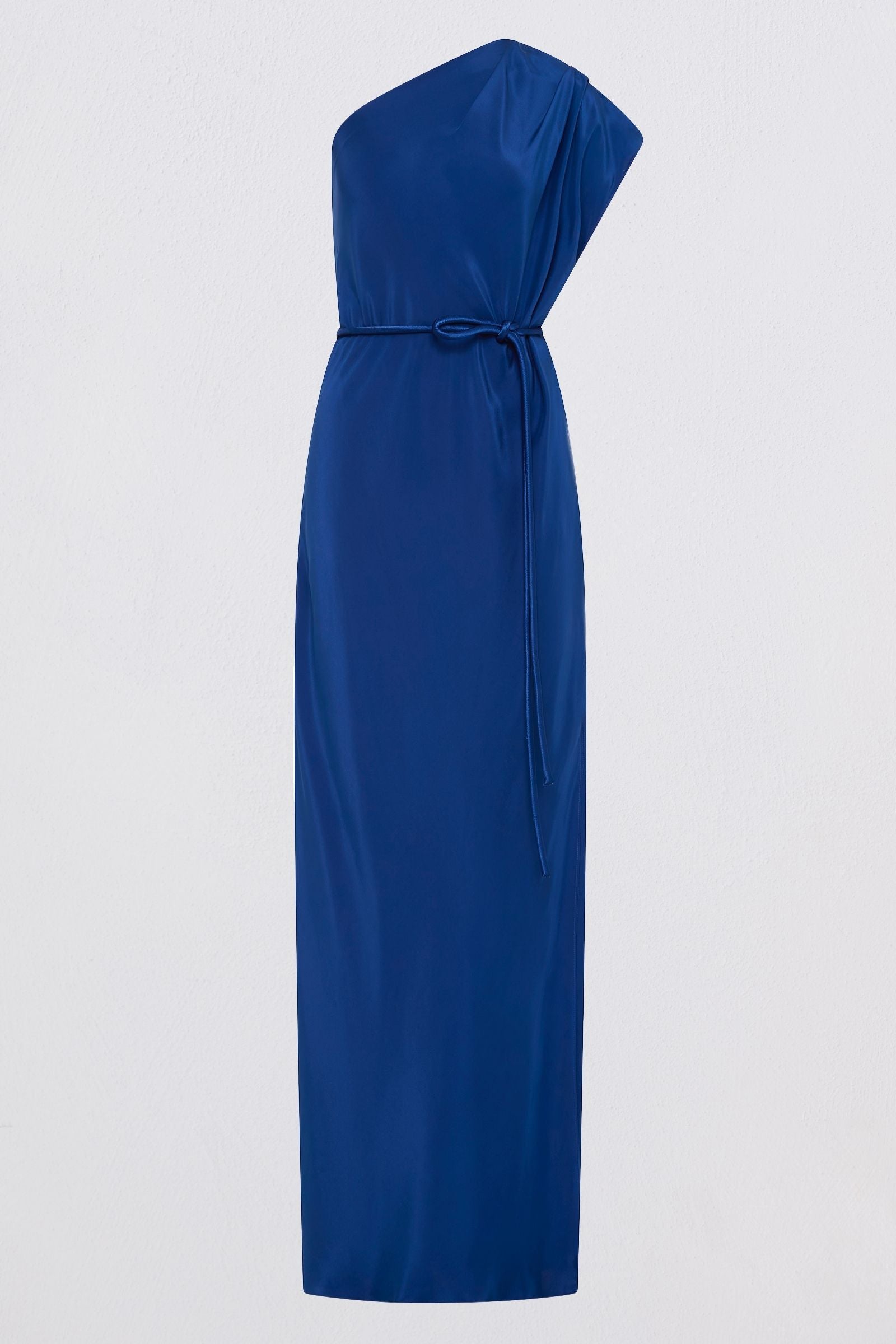 A royal blue one-shoulder midi dress with a draped neckline and a matching tie belt at the waist, shown against a plain light gray background.