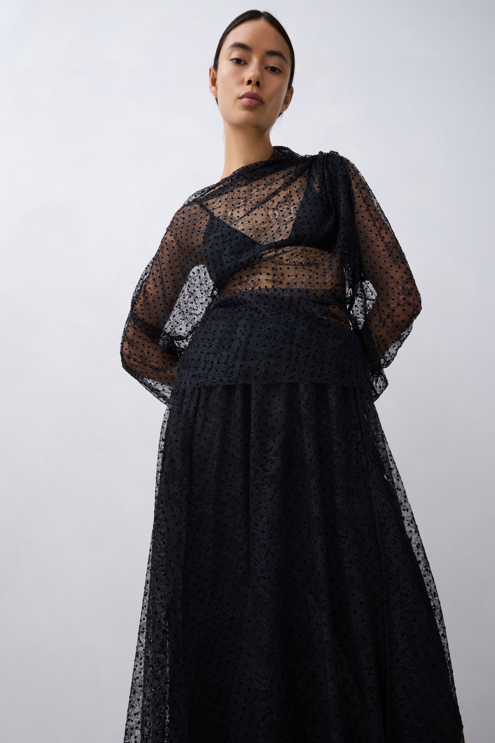 Woman wearing a black lace top against a white background