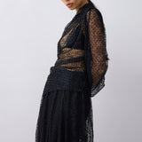 Woman wearing a black sheer dress against a white background