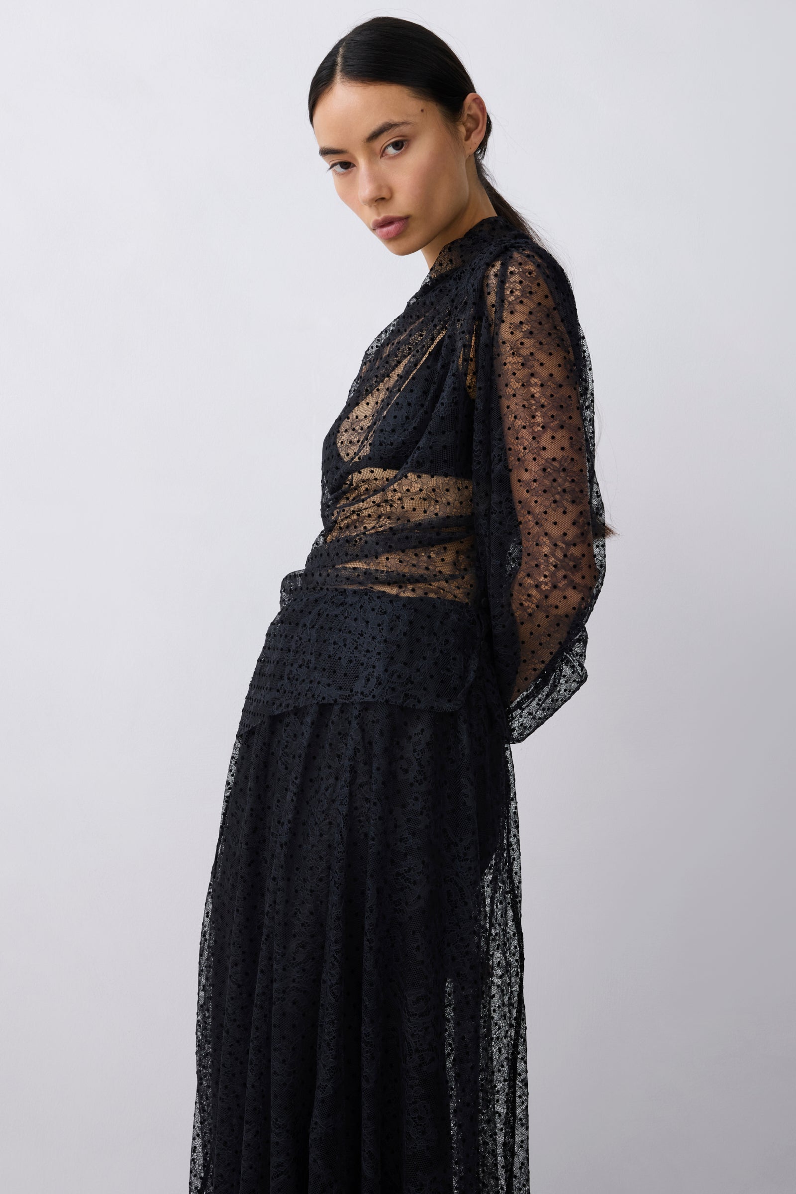 Woman wearing a black sheer dress against a white background