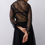 Woman wearing a black lace top against a plain background