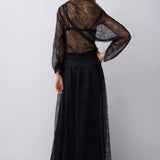 Person wearing a black sheer top and skirt set on a white background