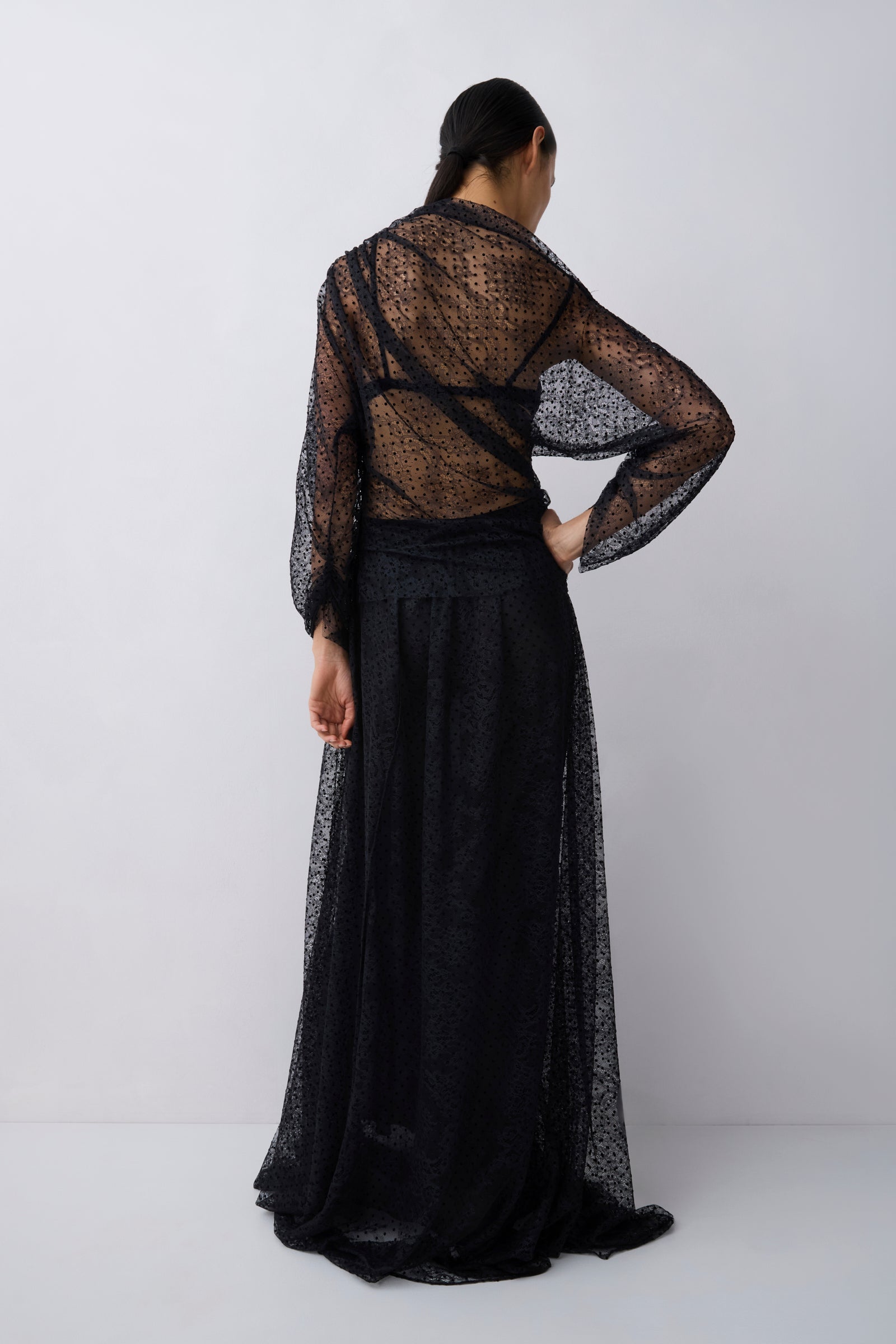 Person wearing a black sheer top and skirt set on a white background