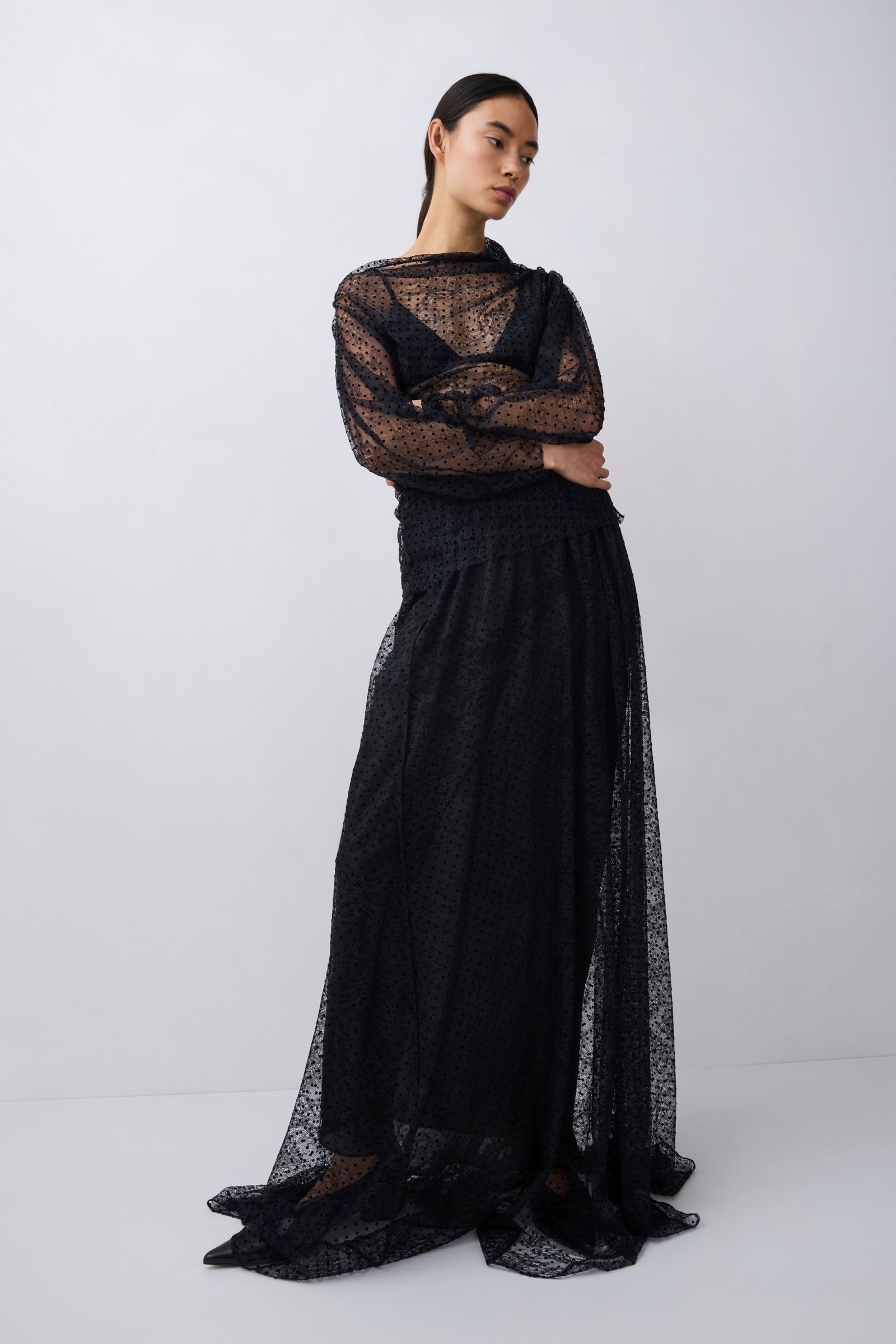 Model wearing a black lace outfit on a white background