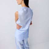 A woman wearing a light blue satin two-piece set, shown from the back in a studio setting with a white background.