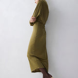 Woman wearing a green dress standing against a white wall