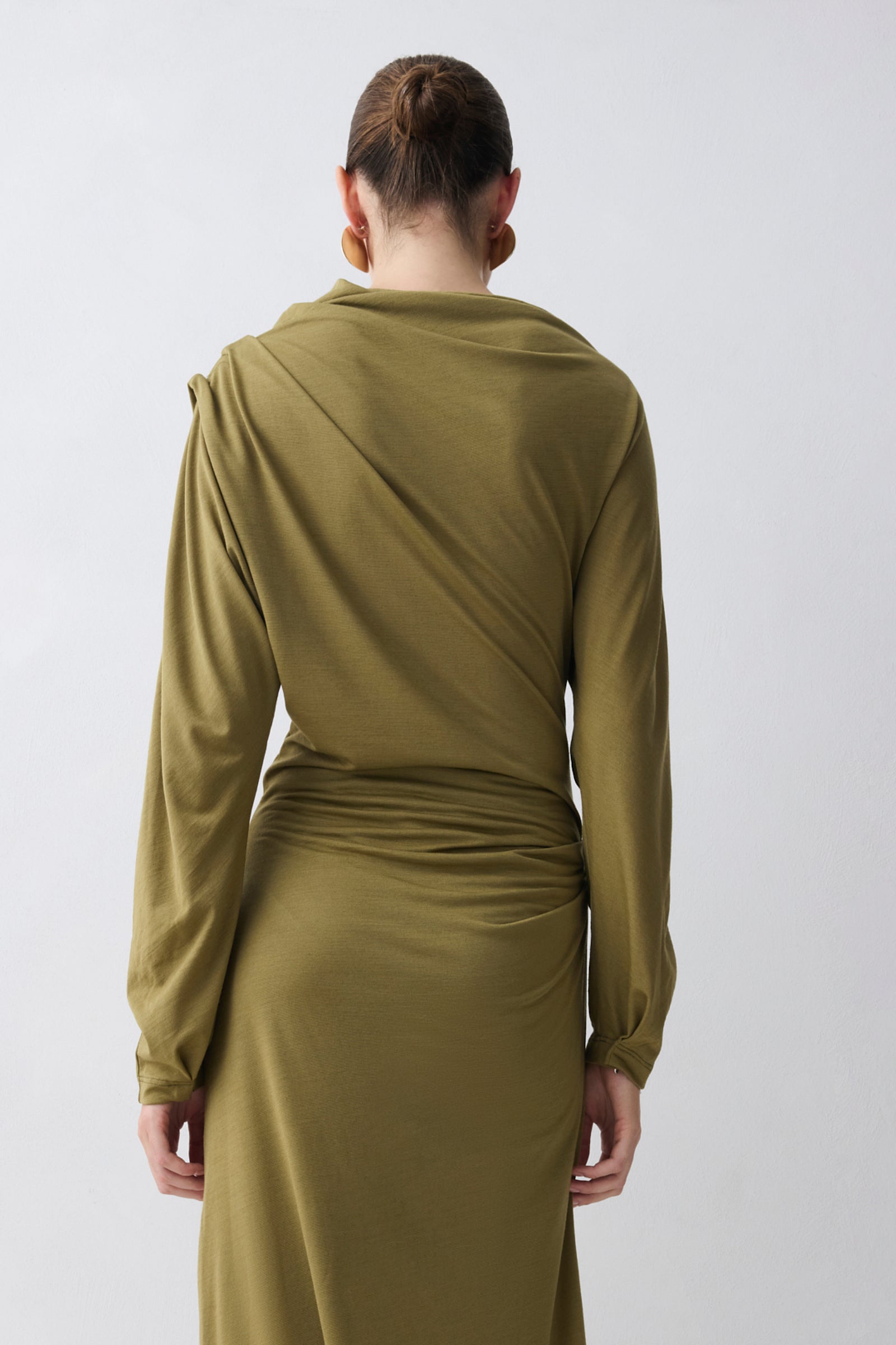 Person wearing a green dress with long sleeves on a white background