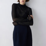 Woman wearing a black top and navy skirt against a white background