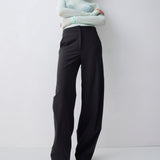 Person wearing a light green turtleneck and black pants against a white background