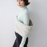 Person wearing a light green turtleneck and black pants with a white background