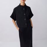 Woman wearing a black outfit with a cape-like top on a white background