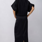 Person wearing a black outfit with a plain background