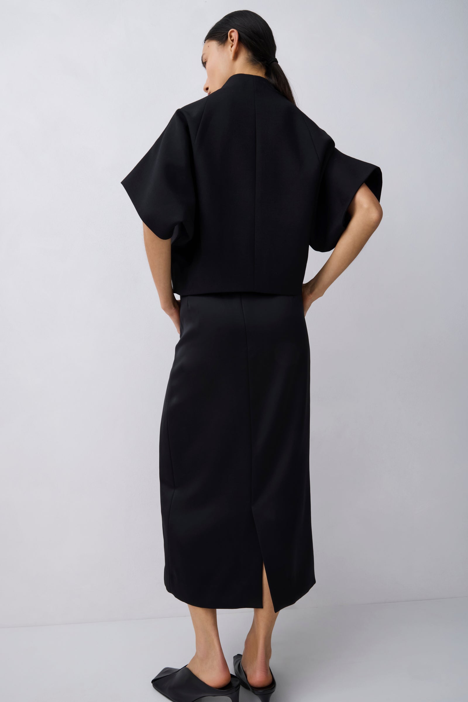 Person wearing a black outfit with a plain background