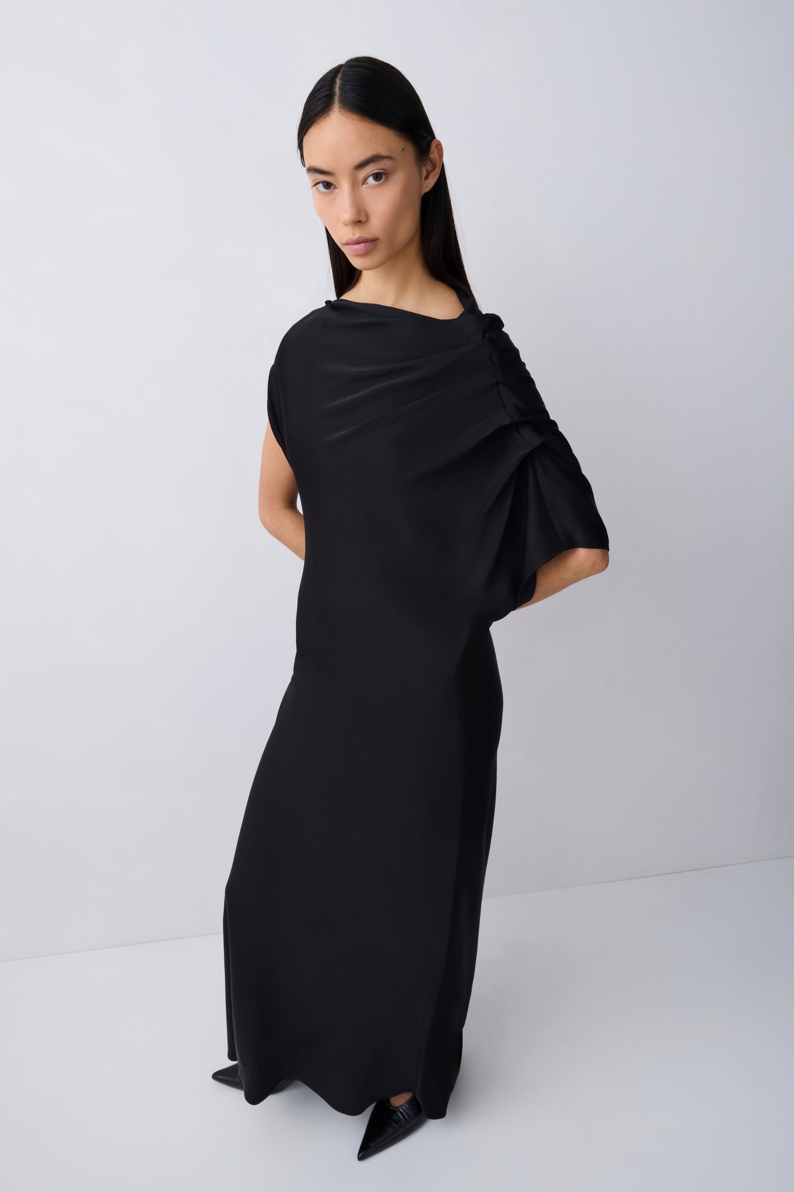Woman wearing a black draped dress against a white background