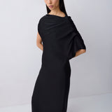 Woman wearing a black draped dress against a white background