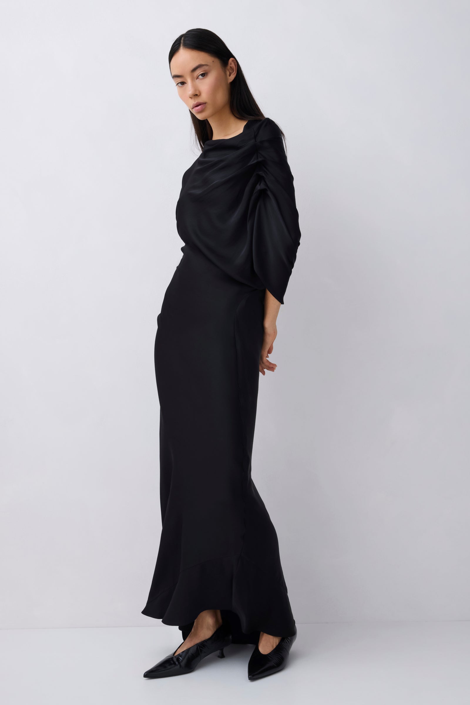 Woman wearing a black dress with a draped effect on a white background