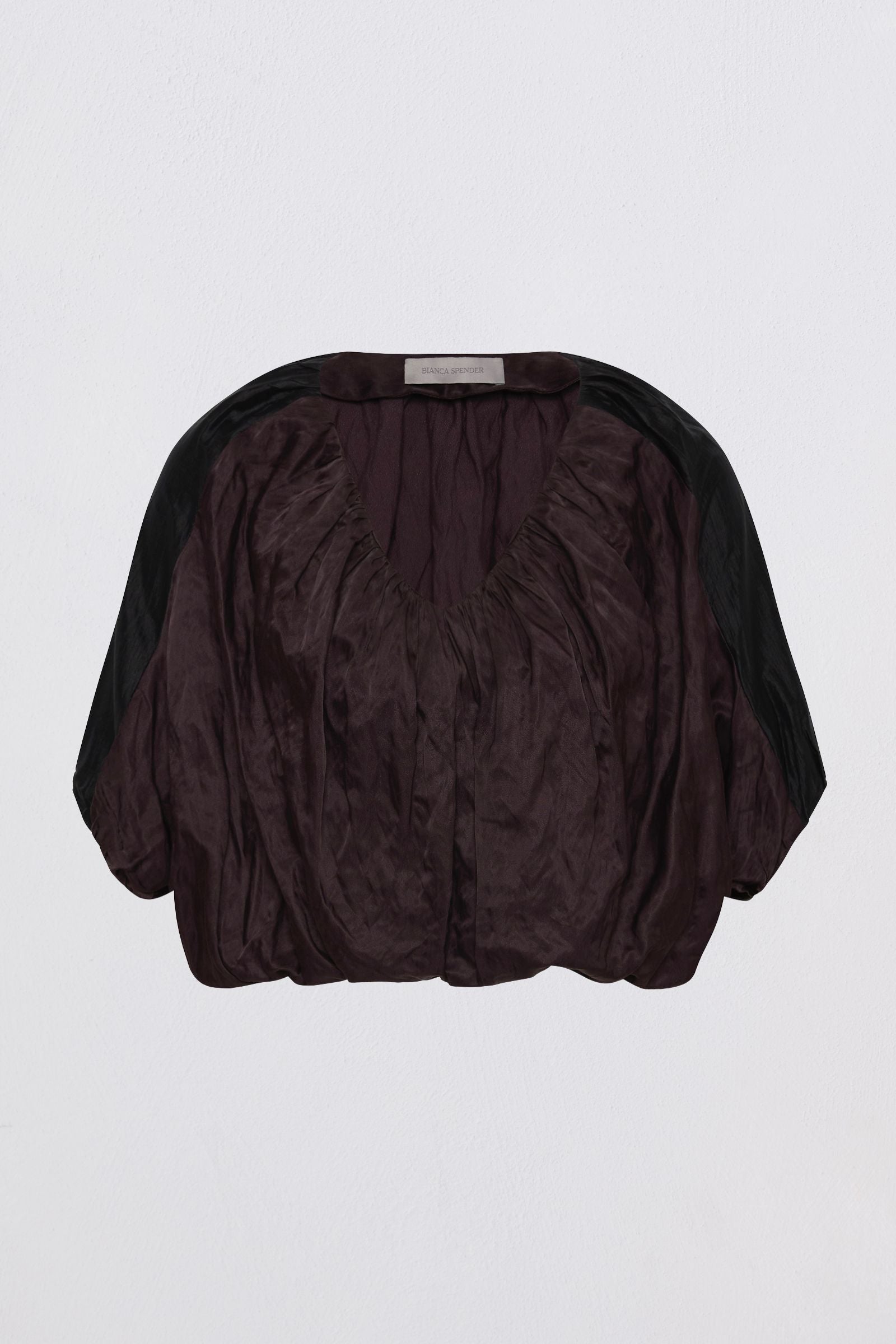 A dark plum purple crinkled blouse with black sheer sleeves, shown from the back against a light gray background.