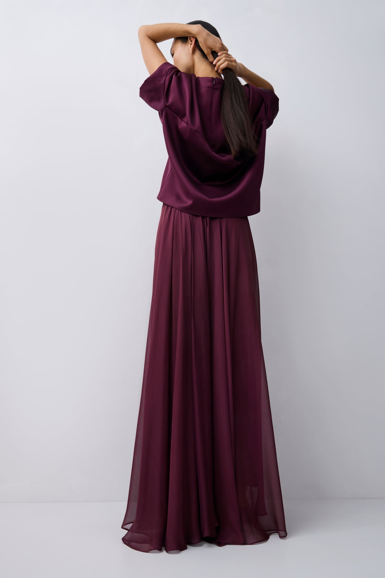 Woman wearing a long burgundy dress against a white background
