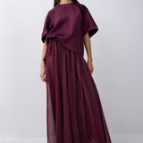 Woman wearing a long burgundy dress against a white background