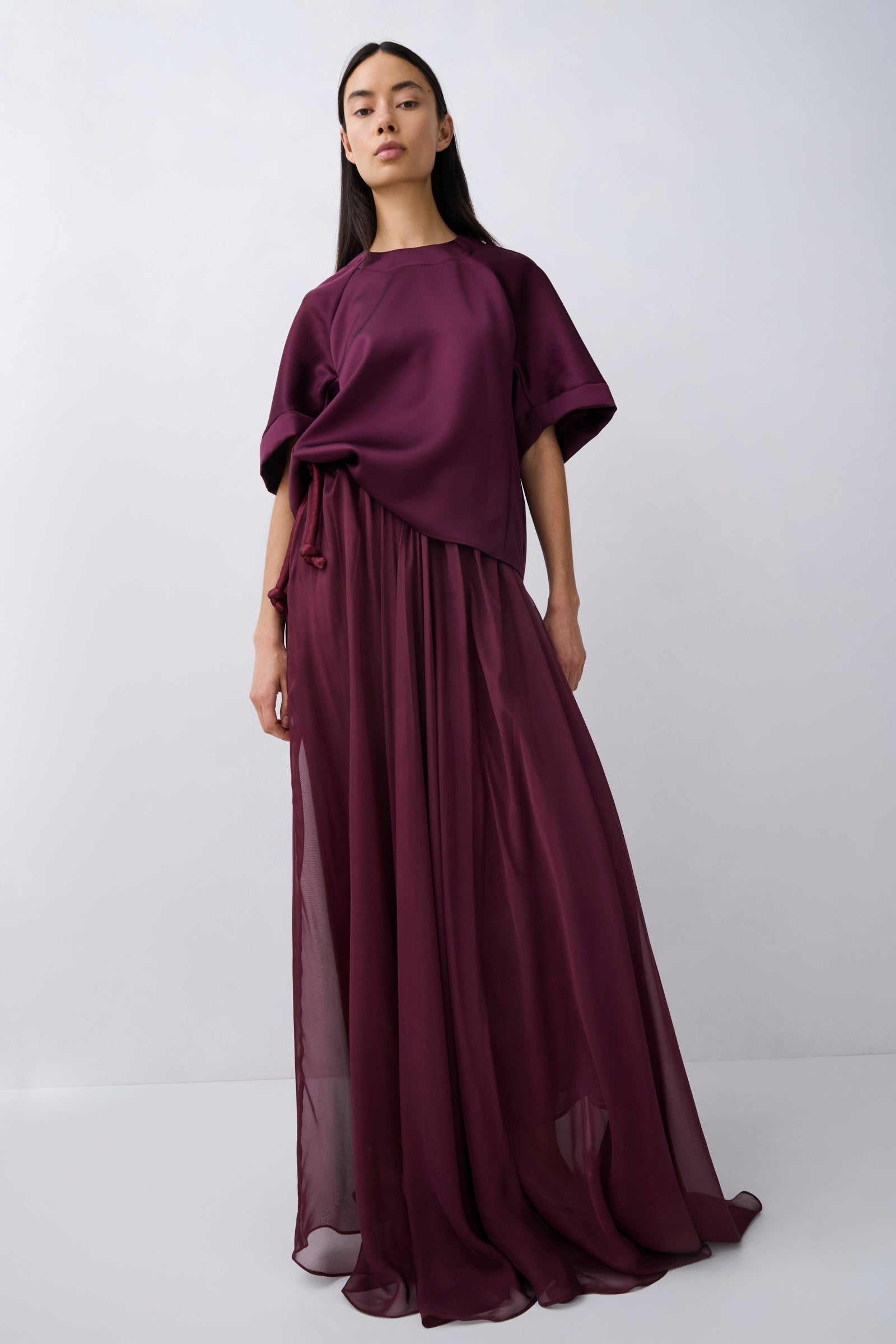 Woman wearing a long burgundy dress against a white background