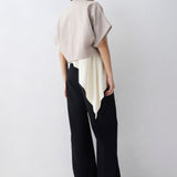 Person wearing a beige top and black pants against a white background