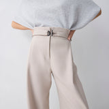 Person wearing a light gray poncho and beige pants on a white background