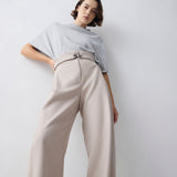 Person wearing a light gray top and beige pants against a white background