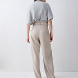 Person wearing a light gray sweater and beige pants on a white background