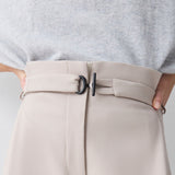 Beige pants with a belt and gray top on a light gray background