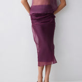 Person wearing a sheer purple top and skirt set on a white background