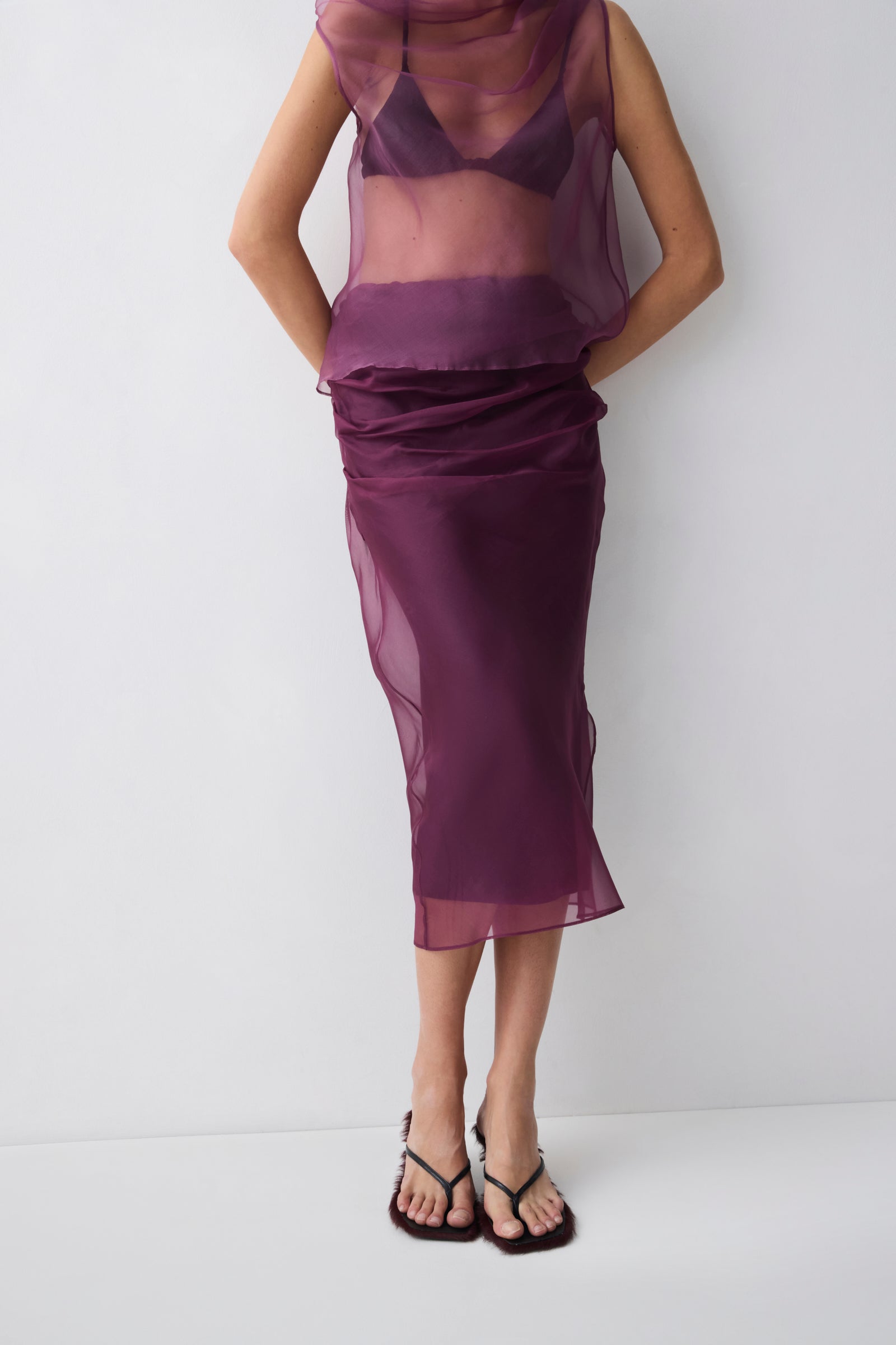 Person wearing a sheer purple top and skirt set on a white background