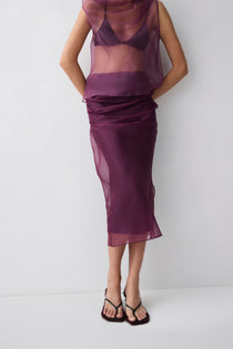 Person wearing a sheer purple top and skirt set on a white background