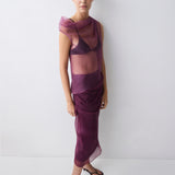 Woman wearing a layered purple outfit against a white background