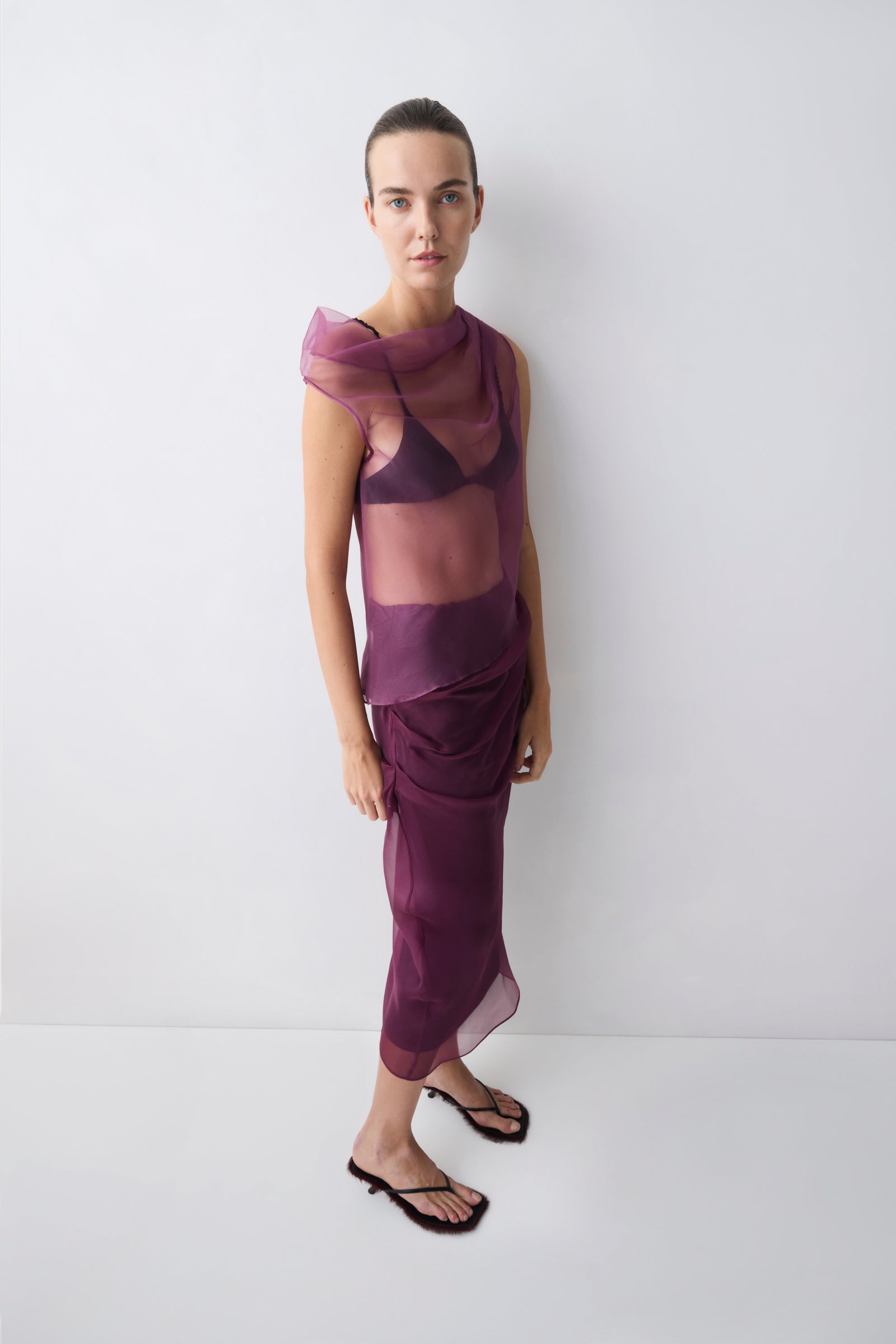 Woman wearing a layered purple outfit against a white background