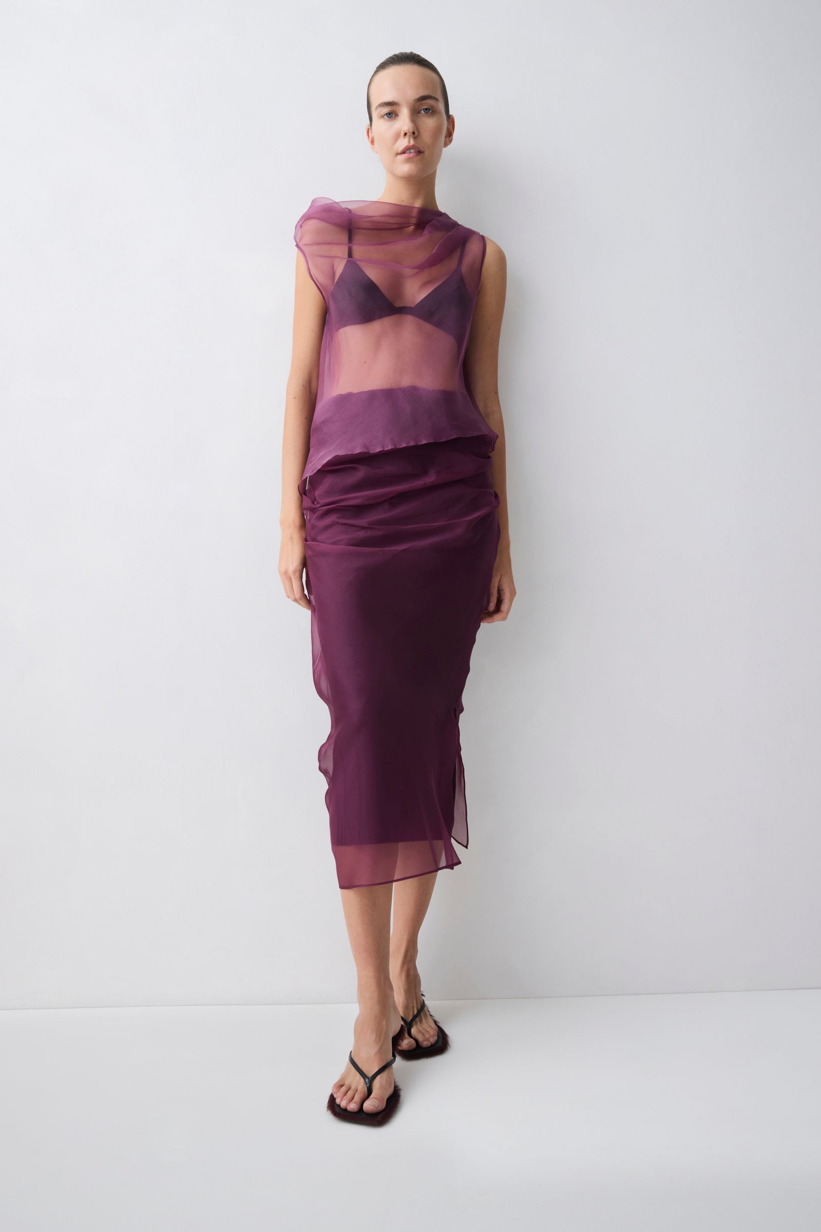 Woman wearing a sheer purple top and skirt against a white background