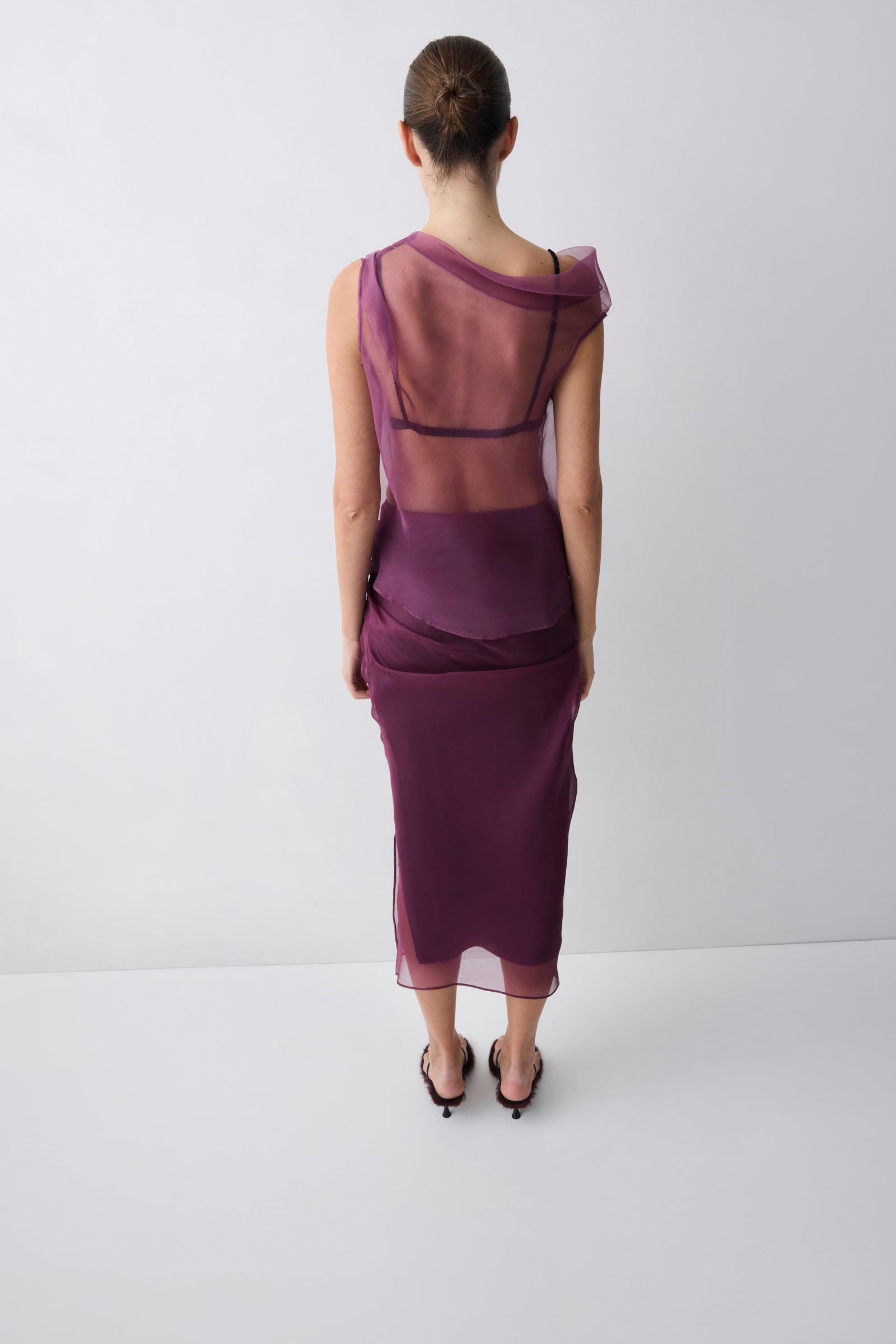 Person wearing a sheer purple dress on a white background