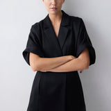 Woman wearing a black coat with a plain background