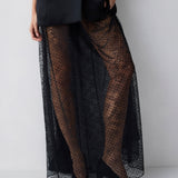 Person wearing a black outfit with sheer black lace overlay on a white background