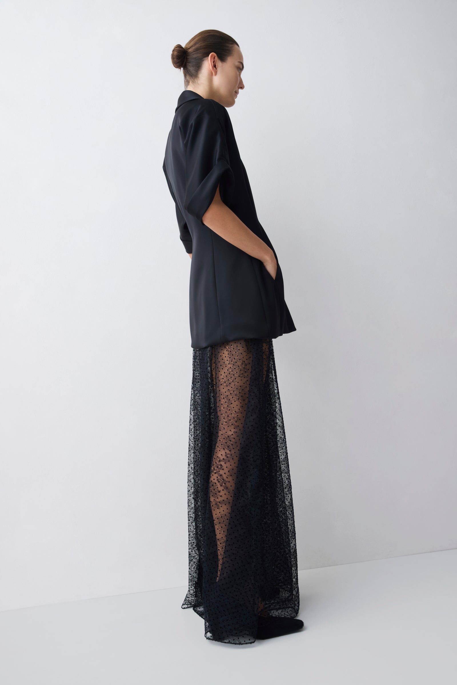 Woman wearing a black outfit with sheer overlay on a white background