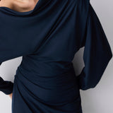 Navy blue draped dress worn by a person on a white background