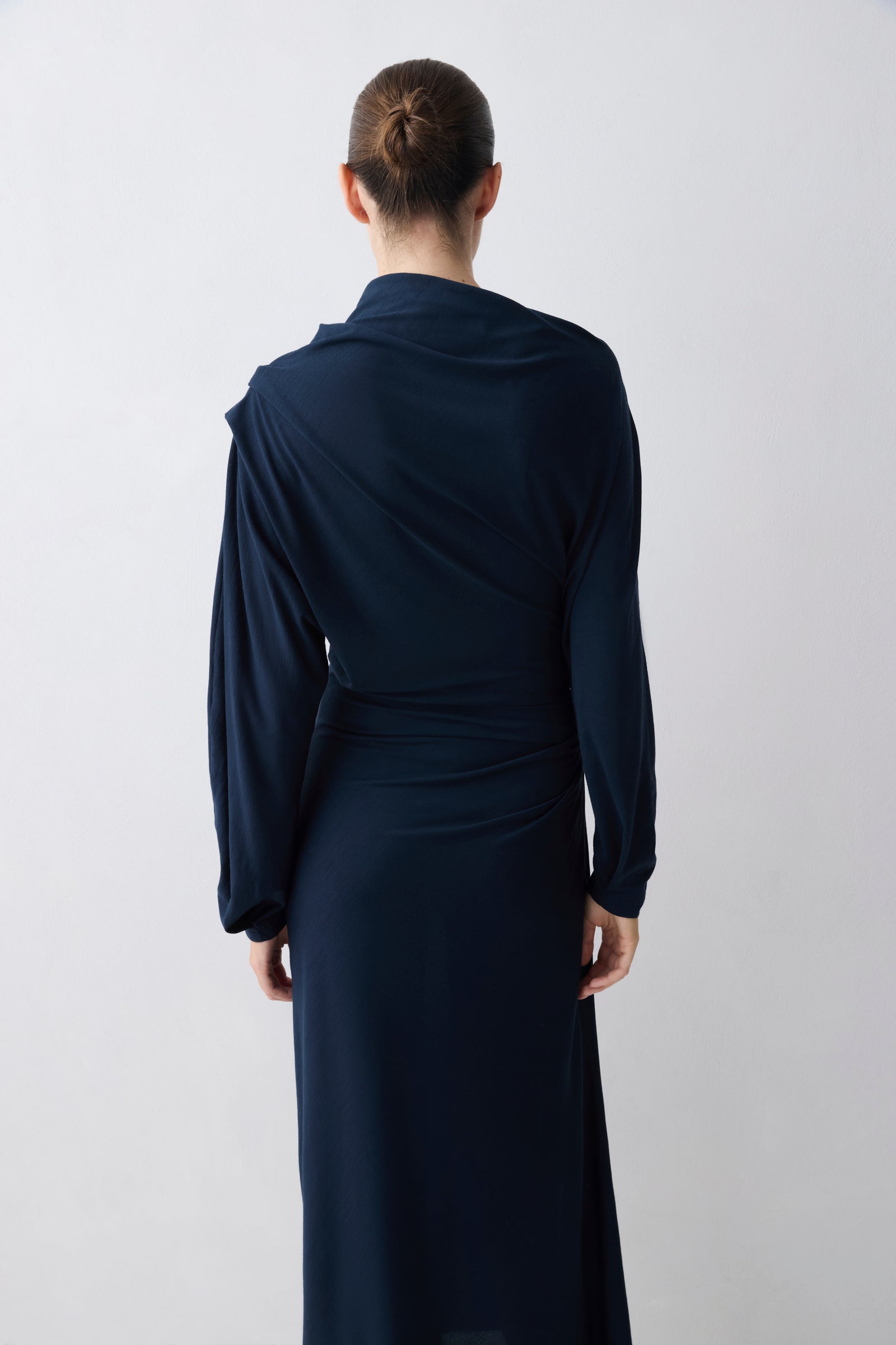Person wearing a long navy dress against a white background